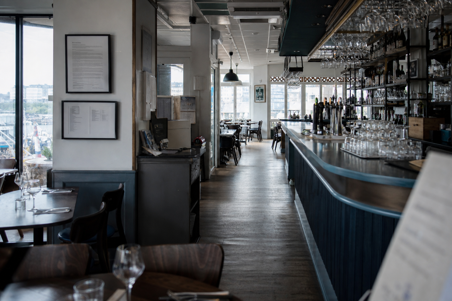 Vue large d’un débit de boissons à Brest, avec comptoir, salle prête au service et affichage flou en arrière-plan.